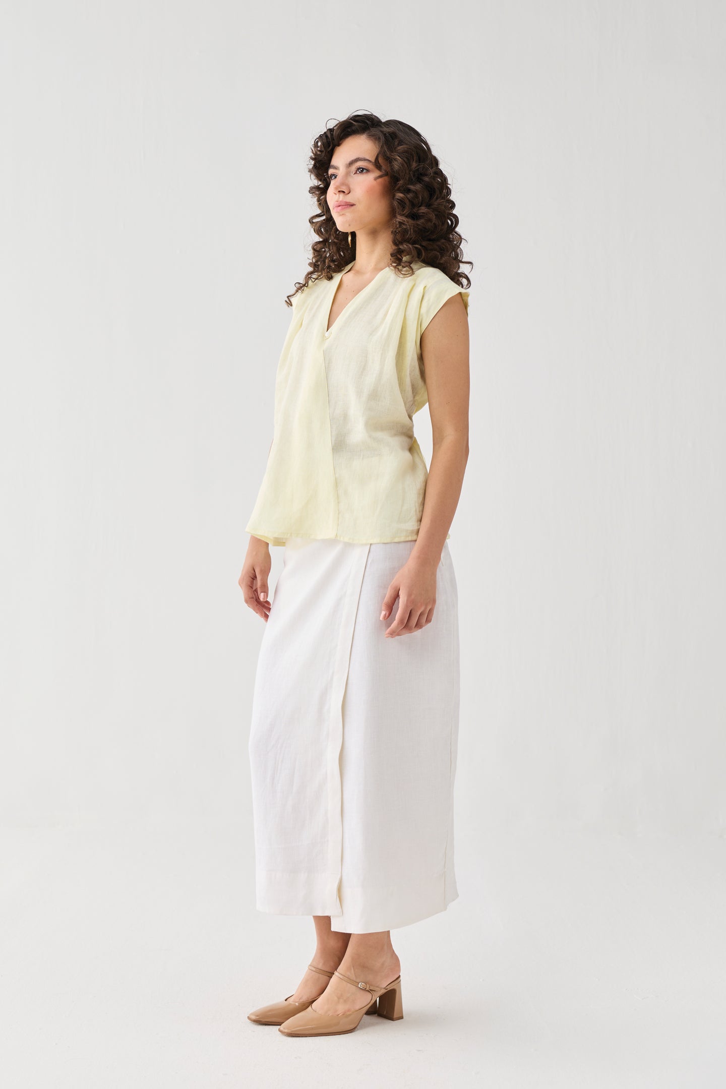 Reistor V-neck Overlap Top in Butter Lemon worn with a white midi skirt and block heels, shown in a side profile with a relaxed fit.