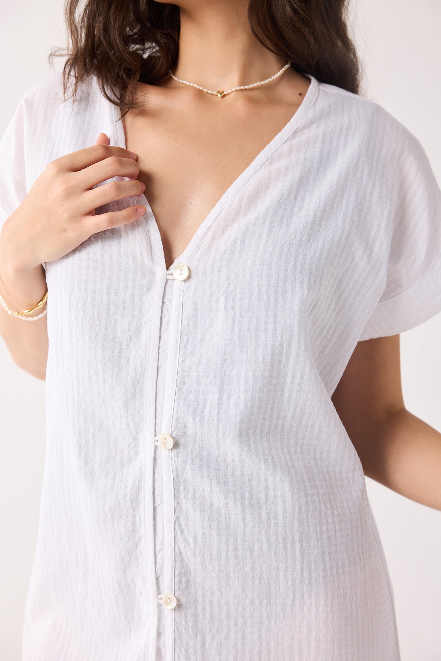 A white button-up dress worn by a person on a white background