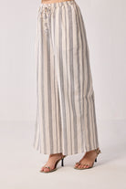 Woman wearing Wide-leg Drawstring Pants in Stripes by reistor, featuring a relaxed fit with vertical stripe detailing and a comfortable drawstring waist.