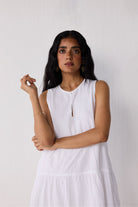 Woman wearing a white sleeveless dress against a plain background