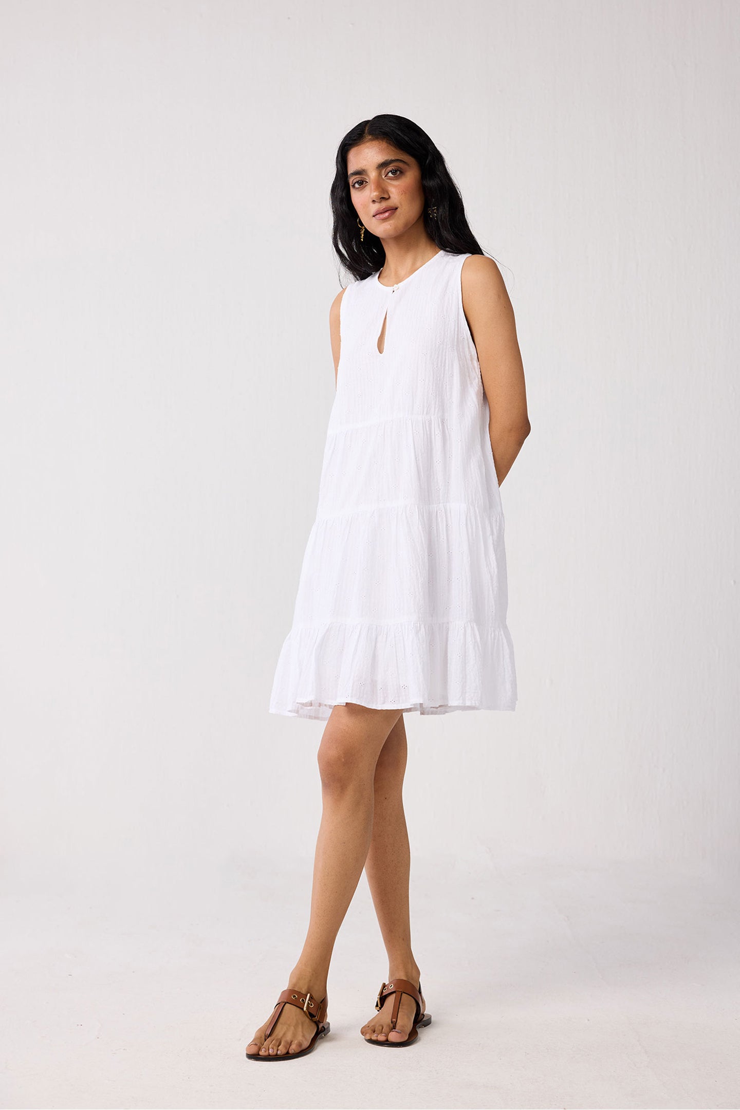 Woman wearing a white sleeveless dress on a plain background