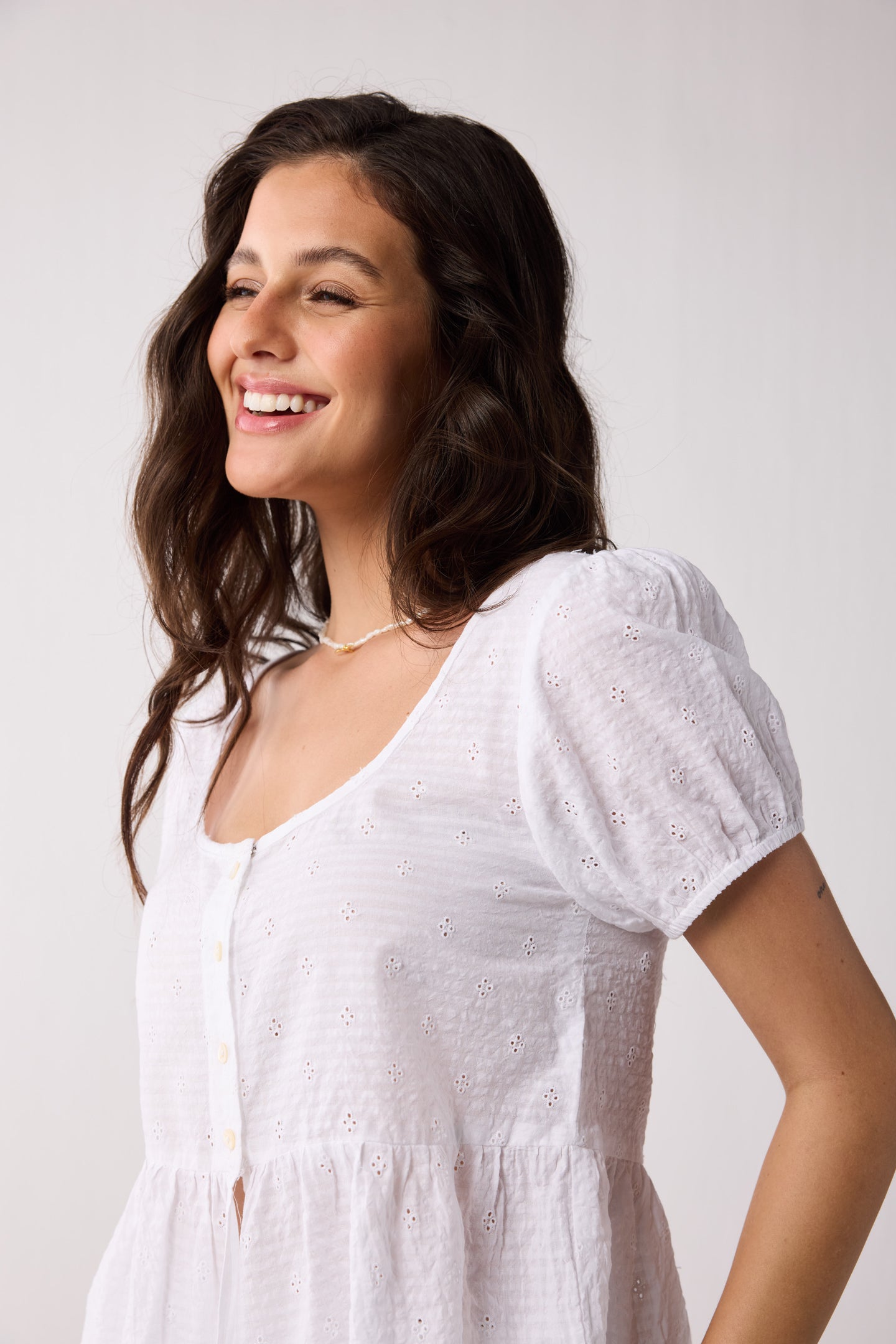 Woman wearing a white top against a plain background