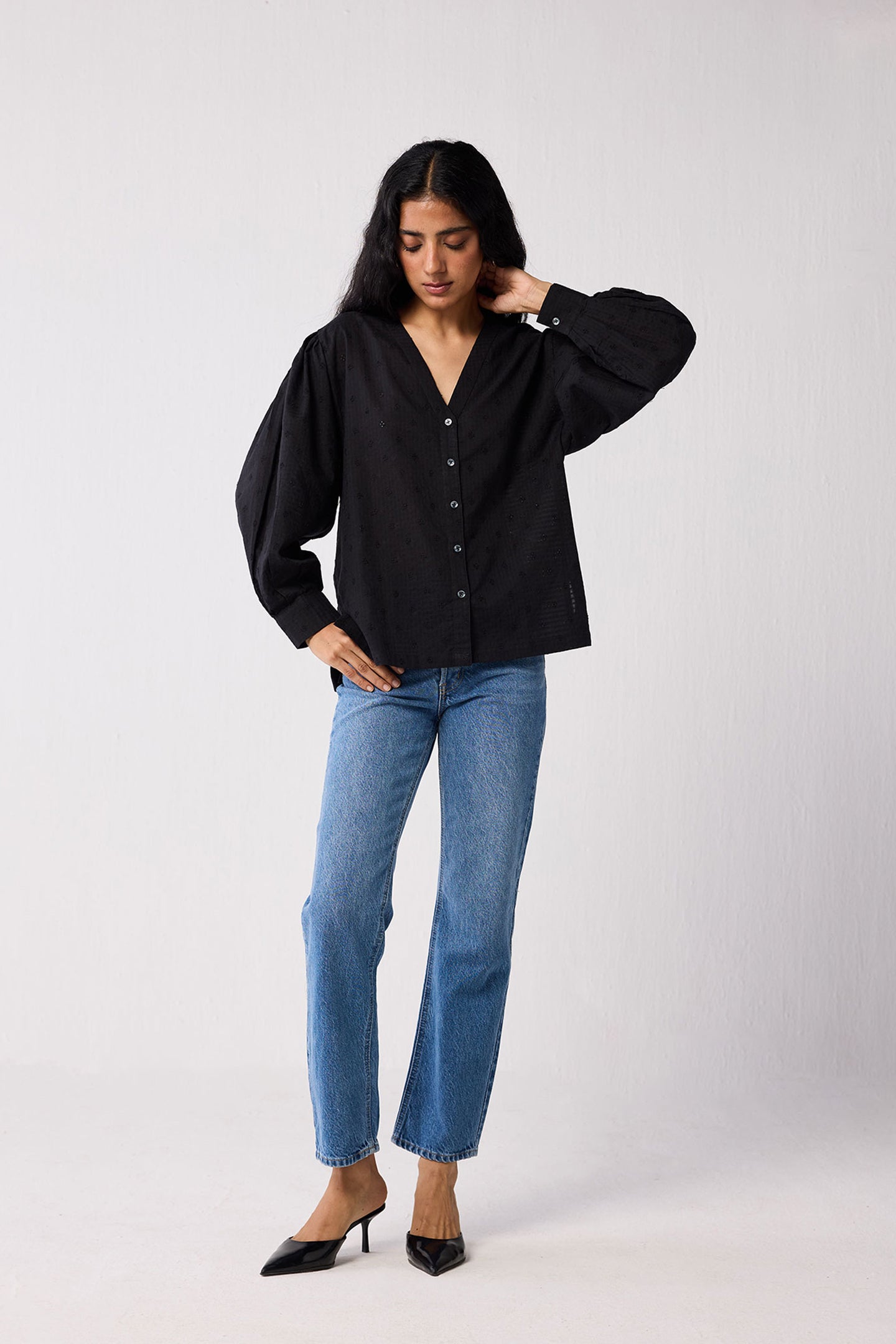 Woman wearing a black blouse and blue jeans on a white background