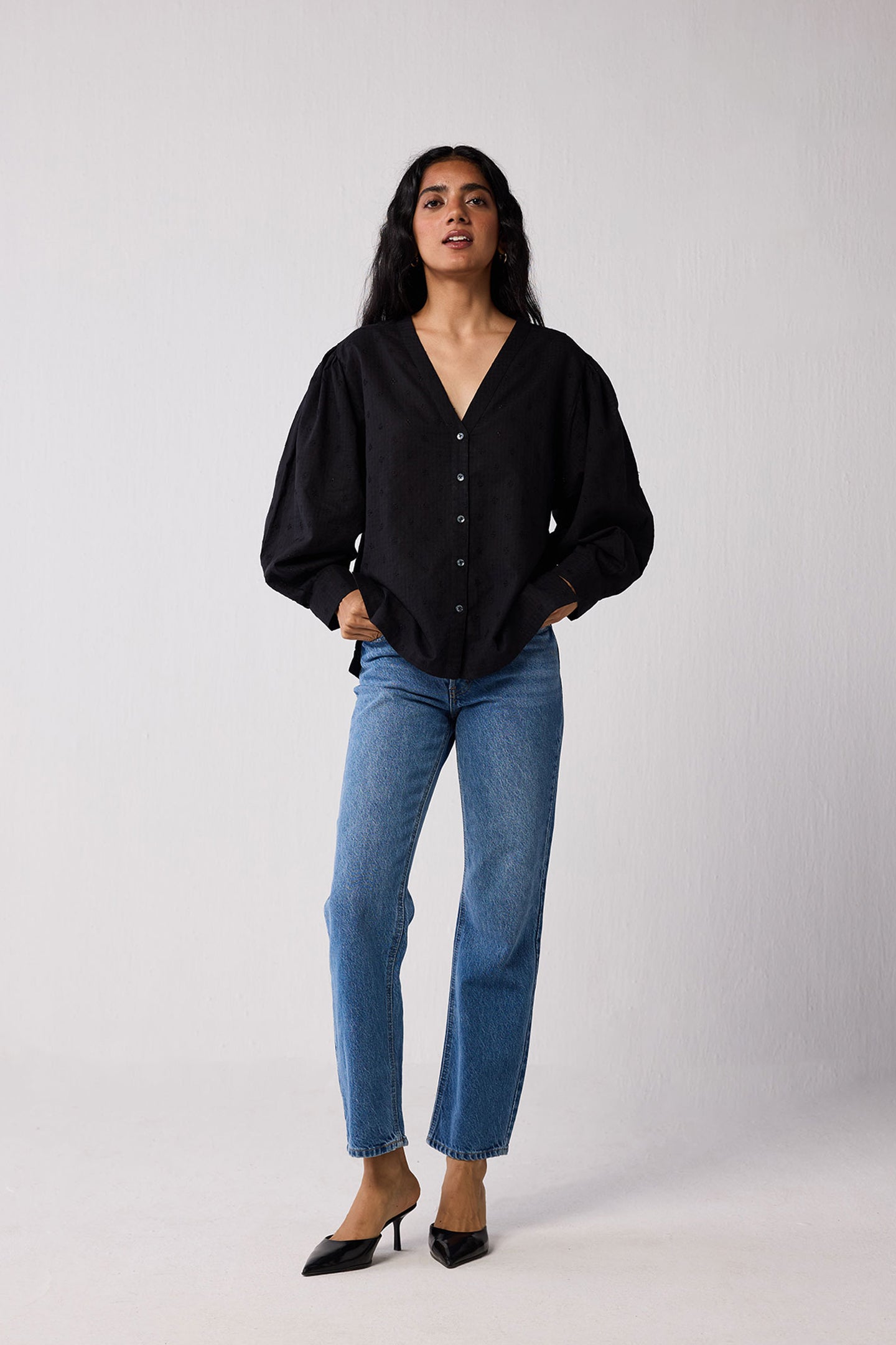 Woman wearing a black blouse and blue jeans on a white background