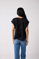 Person wearing a black top and blue jeans on a white background