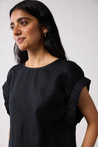 Woman wearing a black top with gathered sleeves against a white background