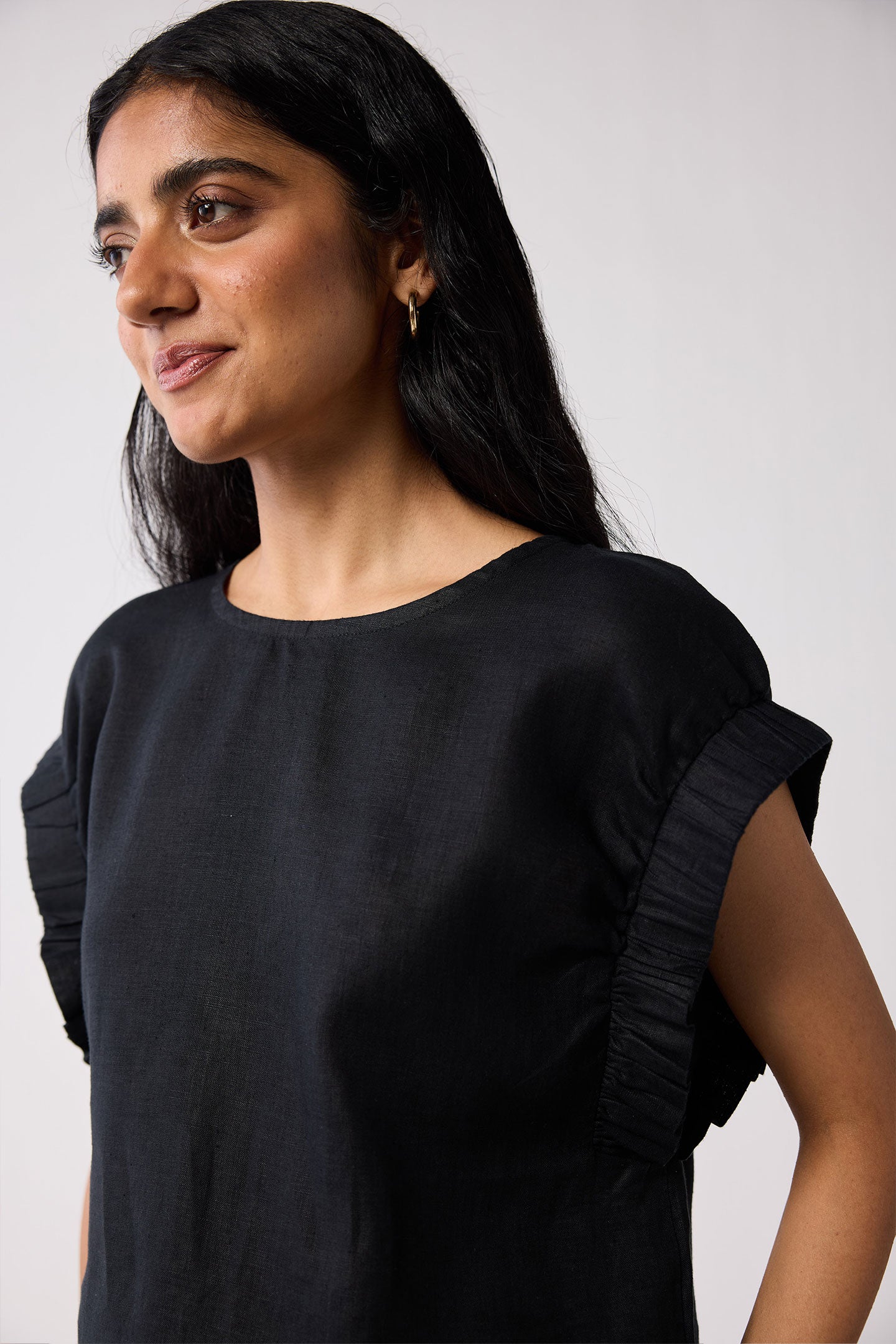 Woman wearing a black top with gathered sleeves against a white background