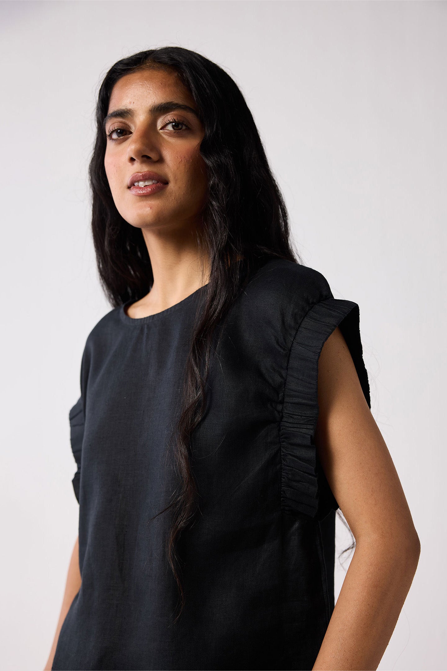 Woman wearing a black sleeveless top against a white background