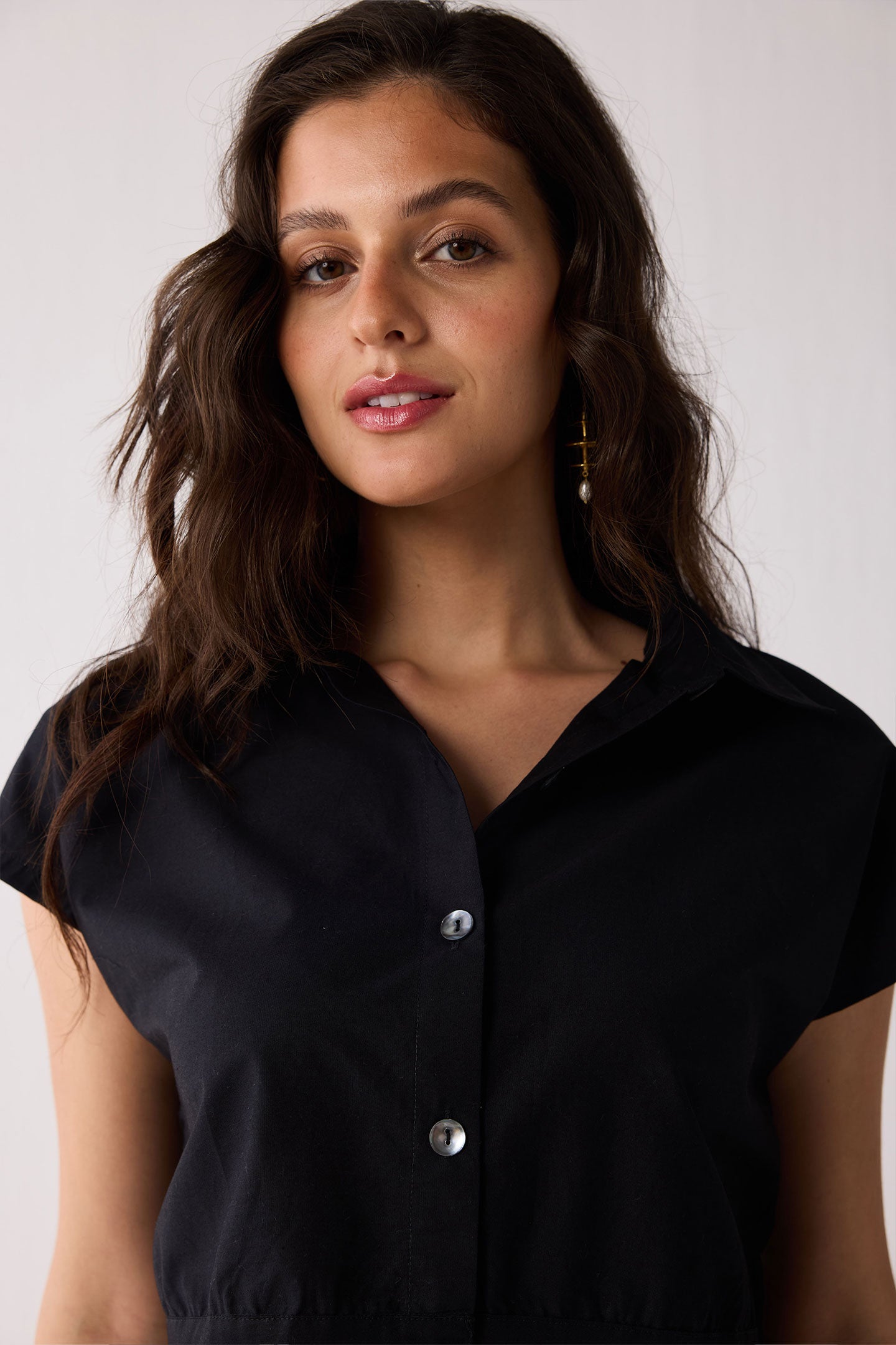 Woman wearing a black shirt with buttons against a plain background