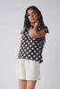 Model showcases Reistor Regular V-Neck Polka Dot Top with Bow Detail through elegant movements and varied poses, with close-up views emphasizing the V-neckline, bow accent, and printed fabric.