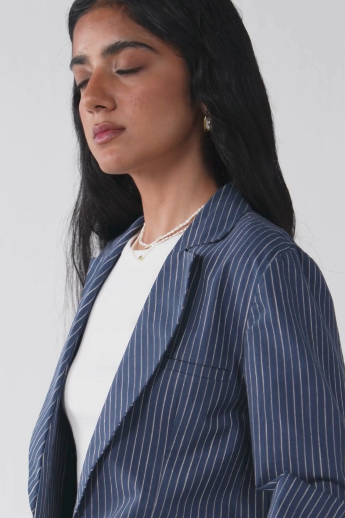 Model brings The Weekday Blazer in Blue Stripes to life through natural, expressive poses, gently highlighting the waist to showcase the smooth fabric movement, stripe detailing, and effortless weekday appeal.