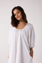 Woman wearing a white blouse against a plain background