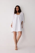 Woman wearing a white dress against a plain background