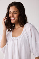 Woman wearing a white blouse against a plain background