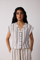Woman wearing a sleeveless striped top and pants against a plain background