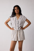 A woman wearing striped shorts against a plain background