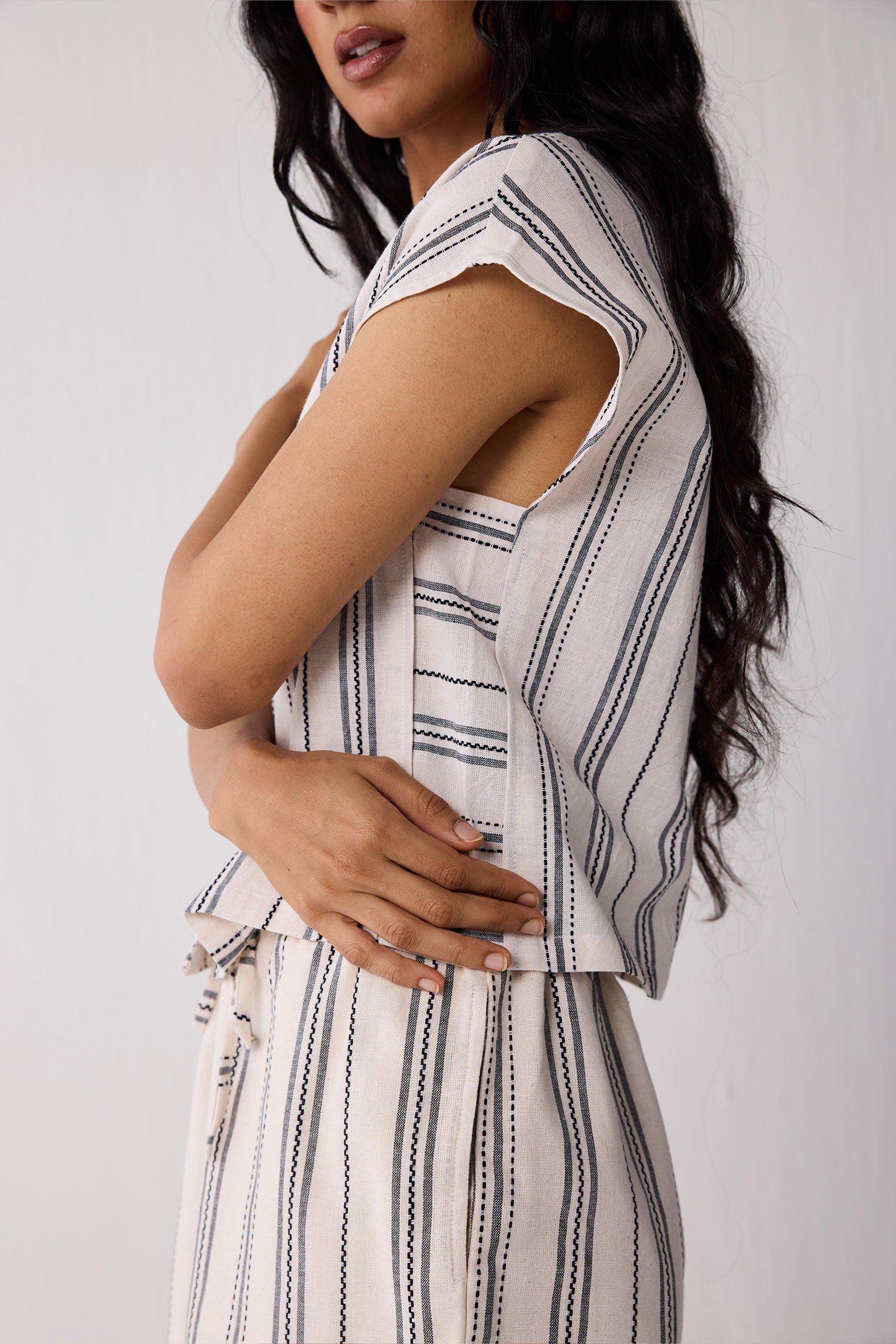 Woman wearing a sleeveless striped top and skirt against a white background