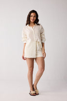 A woman wearing an off-white colored outfit on a white background