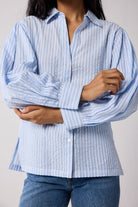 Person wearing a light blue and white striped shirt against a plain background