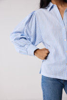 Person wearing a light blue striped shirt against a plain background