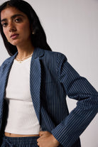Woman wearing a blue pinstripe blazer over a white top against a plain background