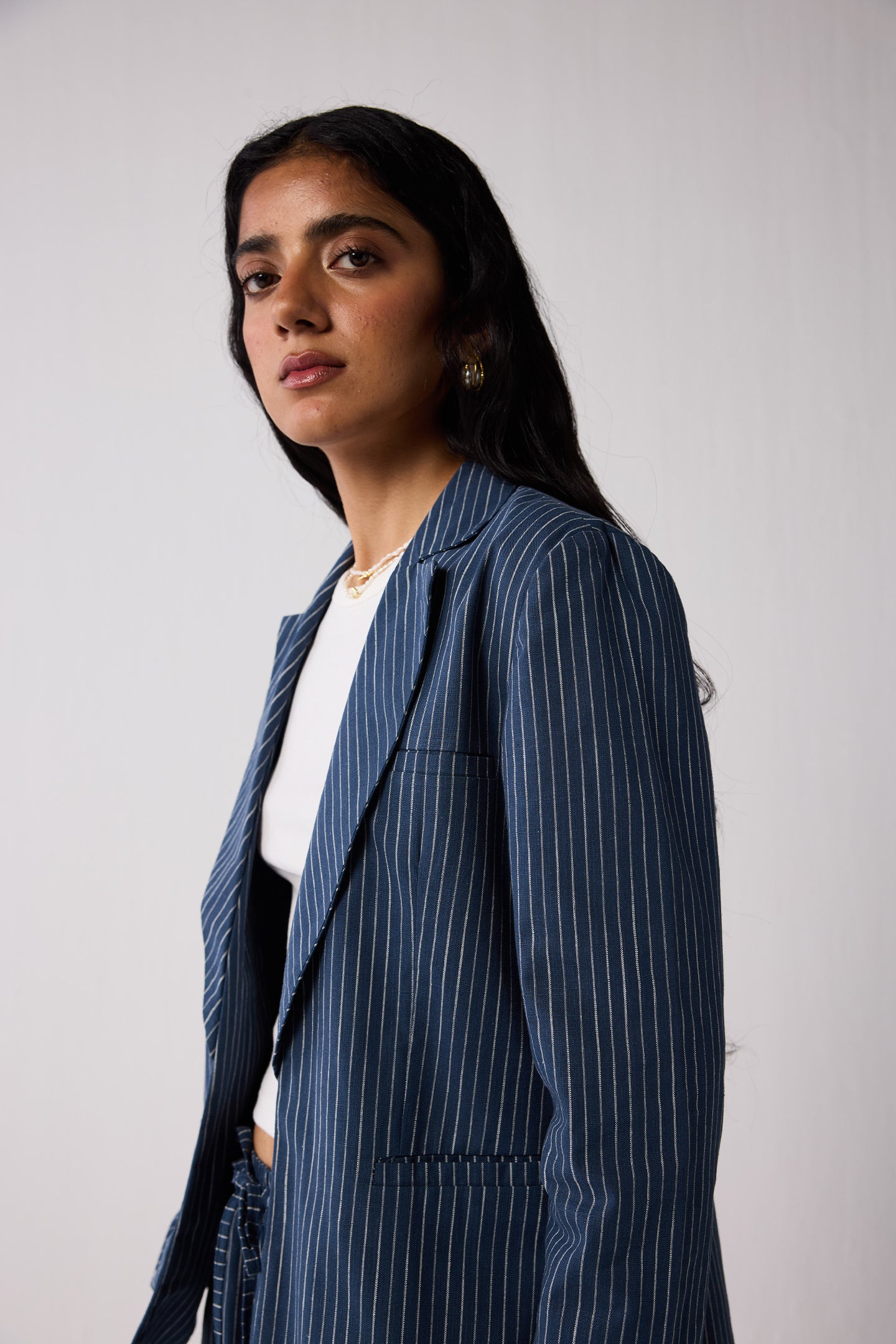 Woman wearing a blue pinstripe suit against a plain background