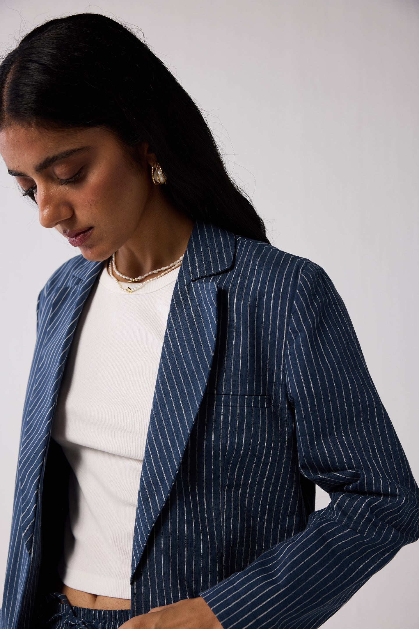 Woman wearing a blue pinstripe blazer over a white top against a plain background