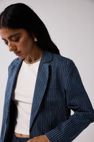 Woman wearing a blue pinstripe blazer over a white top against a plain background