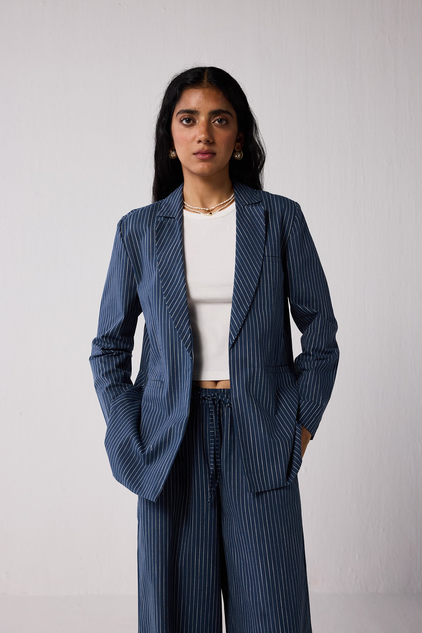 Woman wearing a blue pinstripe suit with a white top against a plain background