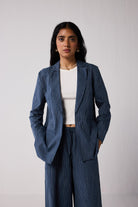 Woman wearing a blue pinstripe suit with a white top against a plain background