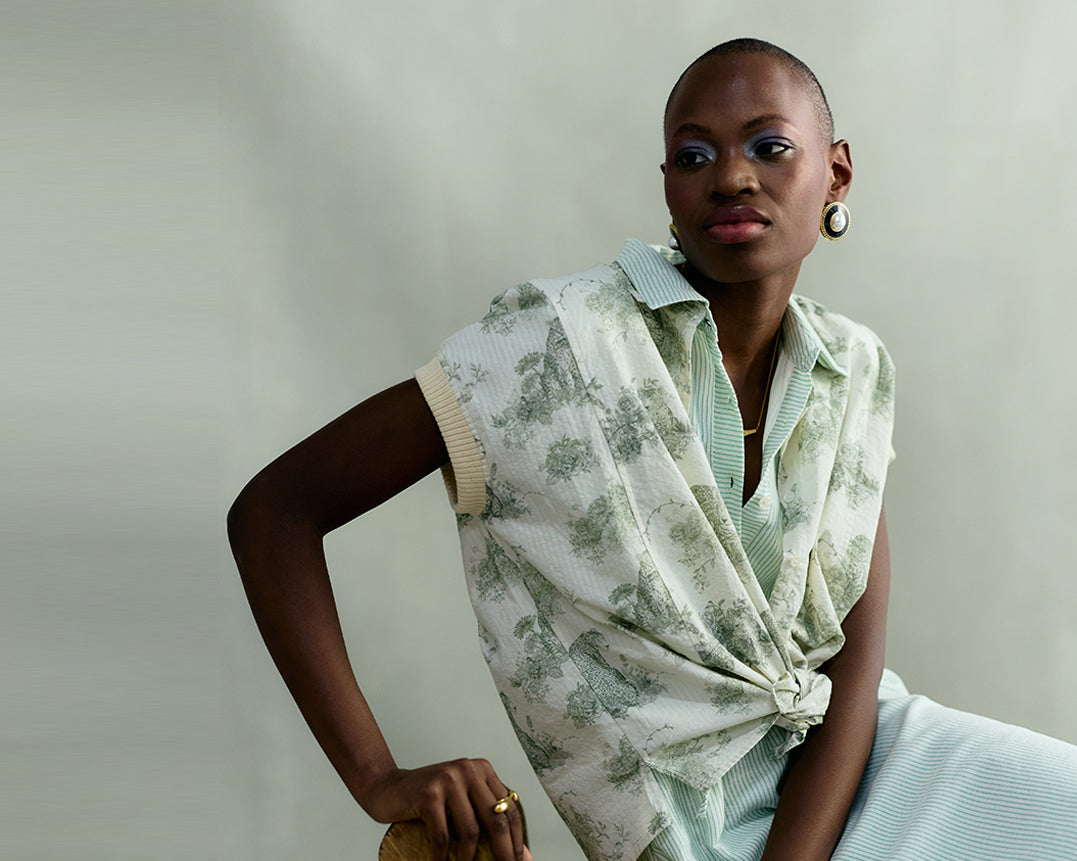 Woman wearing a light green patterned vest over a matching top against a plain background