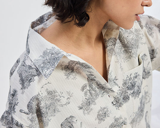 Person wearing a floral-patterned shirt with a neutral background