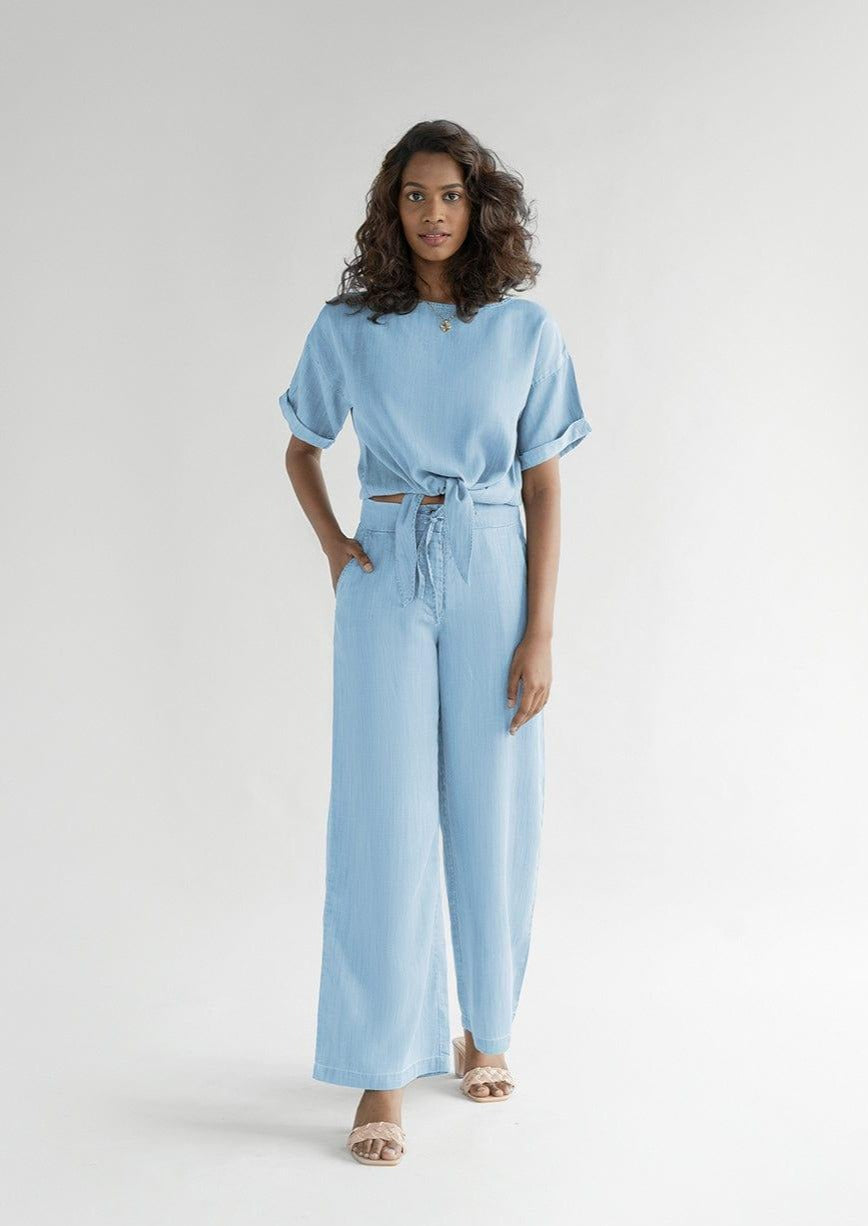 Twist and Sway Top in Blue by Reistor, a relaxed tie-front crop top with rolled short sleeves, breathable fabric, and effortless everyday style for women.