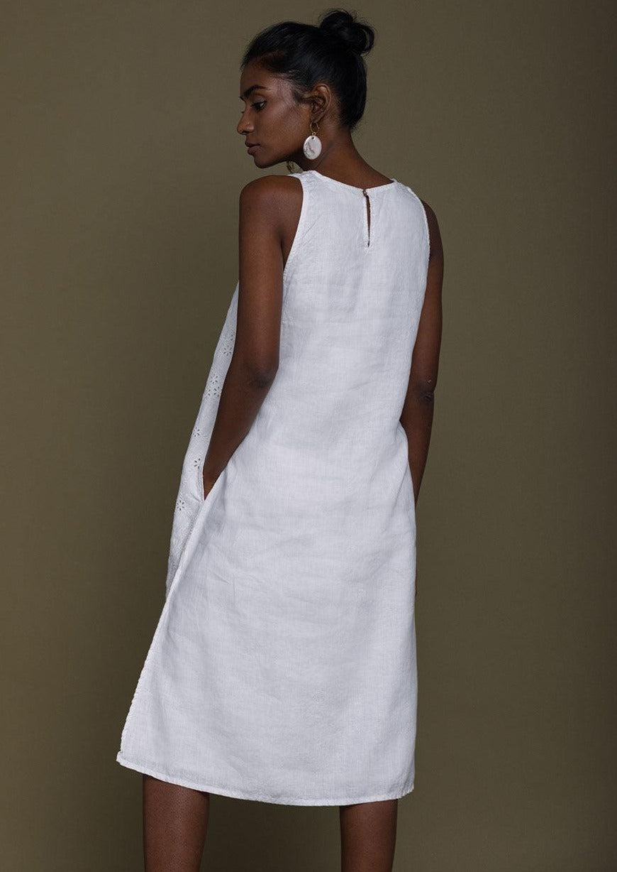 white beach dress with embroidered details all over. The dress is knee length with side slits.