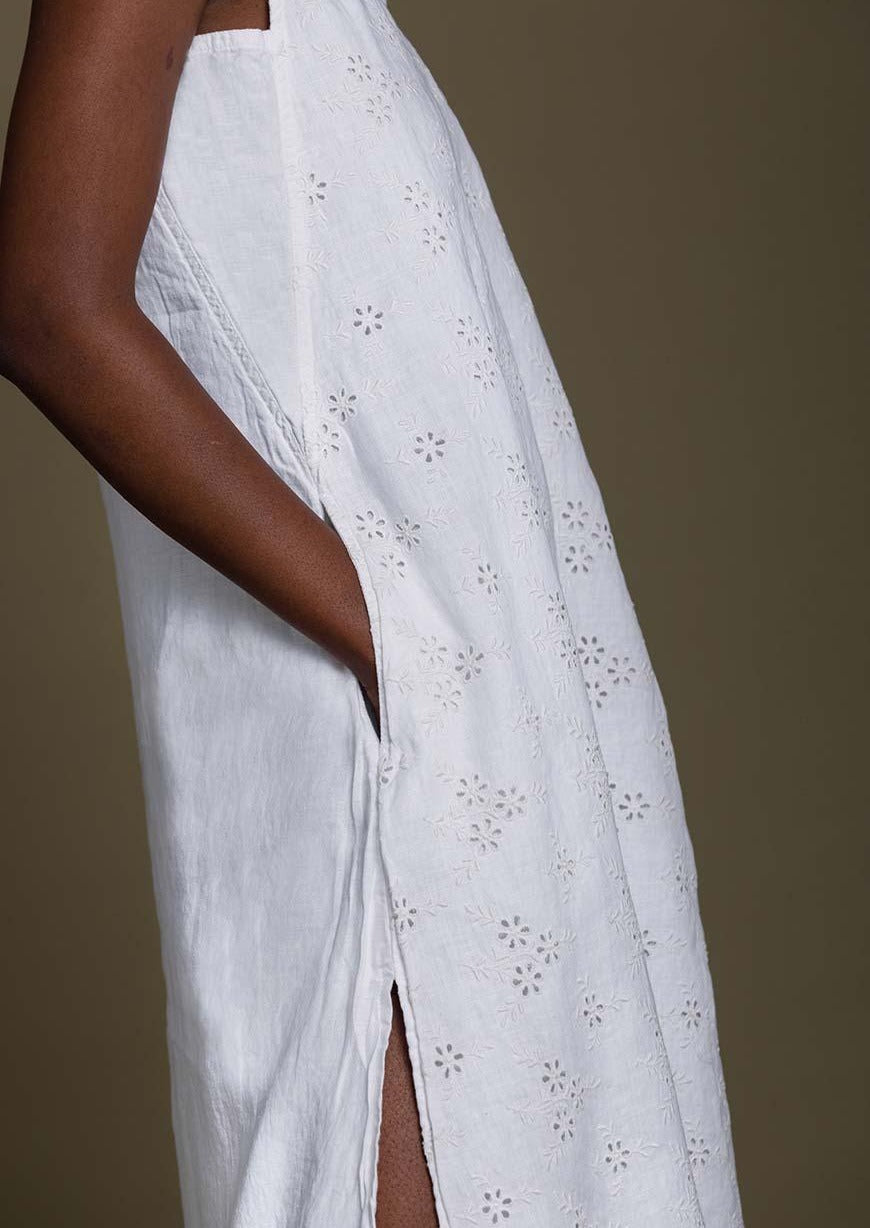 white beach dress with embroidered details all over. The dress is knee length with side slits.