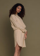 Beige mid length shirt dress with an oversized pocket in the front and a drawstring to tighten the waist.