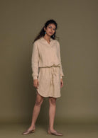 Beige mid length shirt dress with an oversized pocket in the front and a drawstring to tighten the waist.