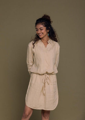 Beige shirt dress with oversized pockets and a drawstring at the waist.