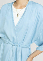Close-up of the Reistor Wrapped in Happiness Overlay in Ocean Blue, featuring a flattering V-neckline, self-tie waist and lightweight fabric for chic layering.